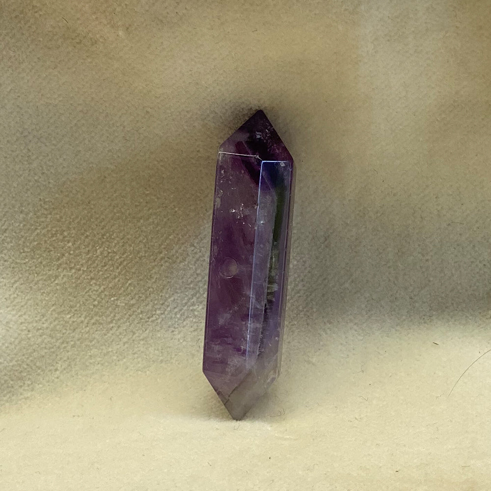 Double-terminated Amethyst Crystal bead.  Cut and polished bead with hole in various places for stringing.  Varied shades of translucent purple with opaque streaks.Size: variable, from 1 to 1 1/2 inches.
