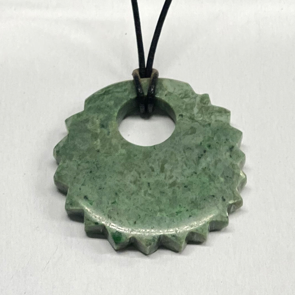 Mendocino California Jade Sun Pendant. Carved and sourced here in Mendocino CA, this unique shape is very pleasing to the eye. The green color is quite deep. The jade used in this piece was sourced from our helicopter trips to our mining claims in the Leech Lake mountain area in Mendocino County, California.