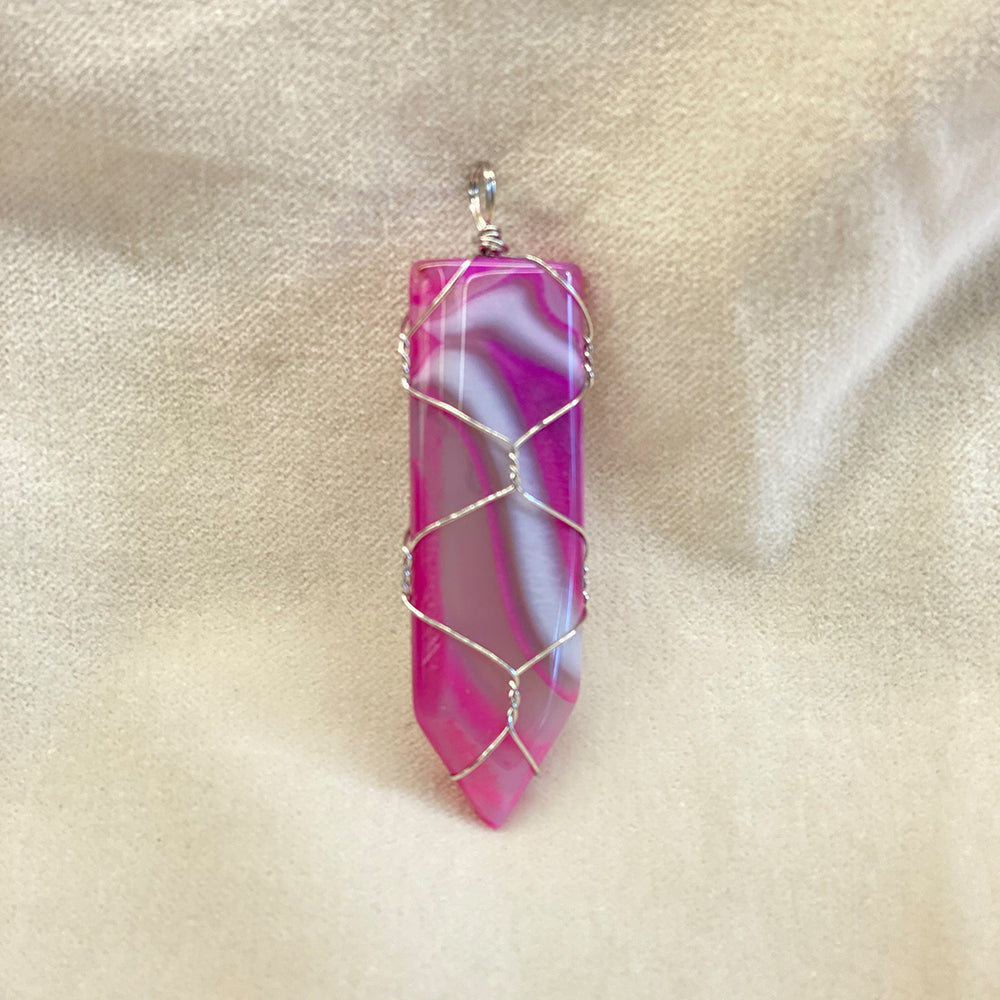 Wire Wrapped Fuchsia Agate Pendant. Artisan made. Stainless steel wrapping. Size varies slightly. Average size: 2.25 x .75 inches. It has been said agate has a stabilizing effect.
