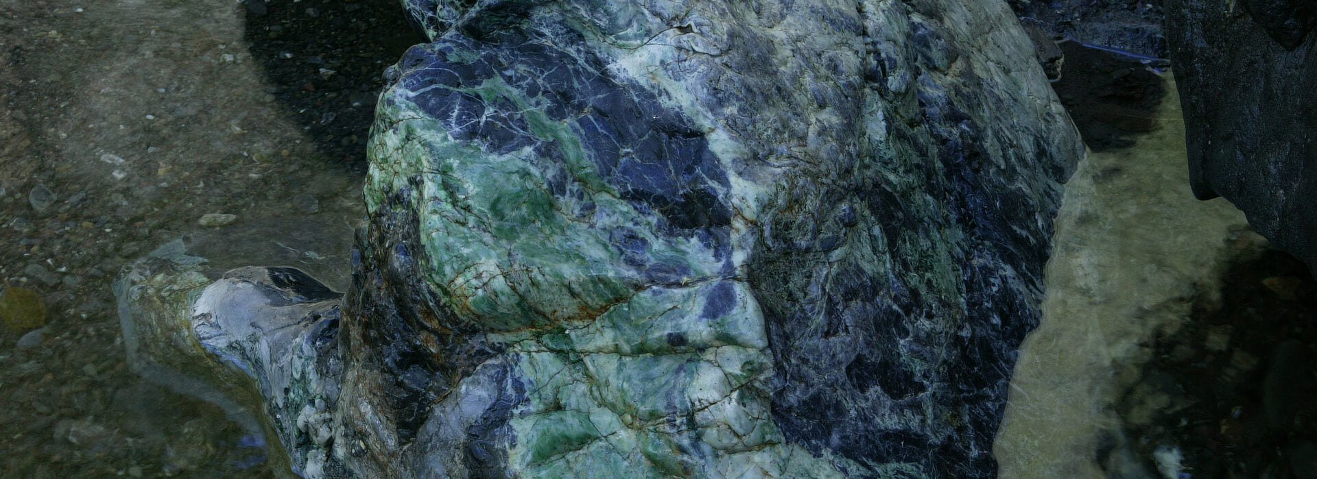 Extraordinary blue, green, white multicolored jade boulder in stream bed, Trinity Mountain wilderness, Cailifornia. 