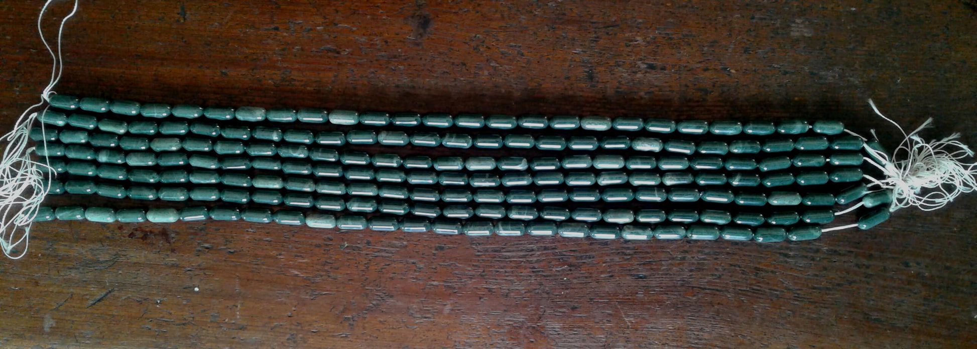 Exquisite California Jadeite beads.  Gun Blue Green color with White crystalline accents.  Tic tac shaped beads are over 1/2" long x 1/4" diameter.  Strands are 16" in length.  Artisan quality.  Sourced from Clear Creek, in the San Panoche Mountains of San Benito County, CA