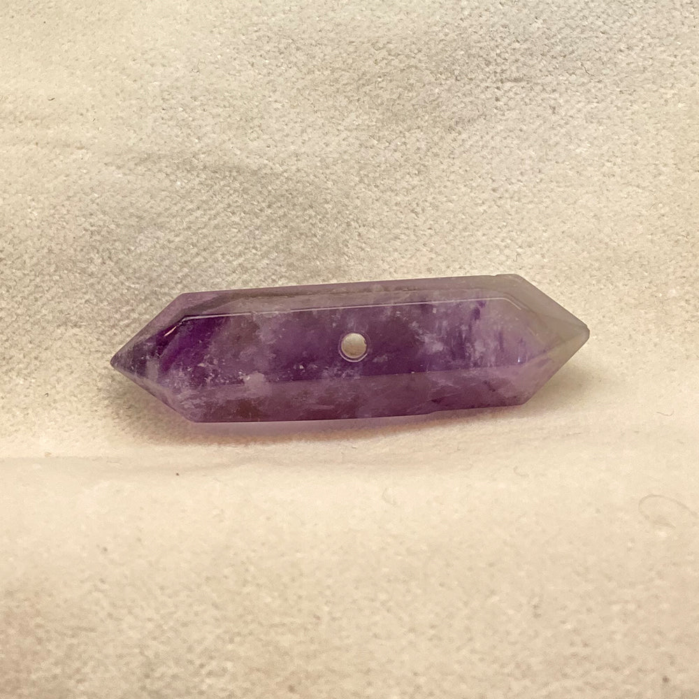 Double-terminated Amethyst Crystal bead.  Cut and polished bead with hole in various places for stringing.  Varied shades of translucent purple with opaque streaks.Size: variable, from 1 to 1 1/2 inches.