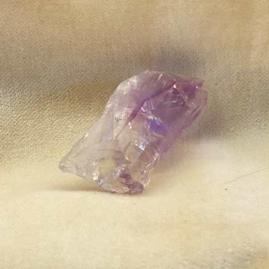 Amethyst Crystal Point.  Clear to purple coloring.  Naturally occurring, unaltered shape and structure.  Piece pictured is approx. 1.5 inches long.