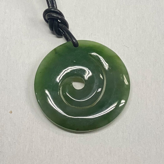 Jade Maori Style Spiral Symbol Pendant.  When held to the light this piece is light green and very translucent.   I purchased this unique piece for resale at the Big Sur Jade Festival.  The design represents the unfurling fern and symbolizes a new beginning. 
