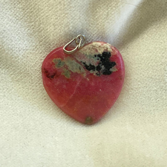 Rhodonite Heart Pendant with stainless steel ring.  Size: approx. 1 inch.  Artisan made. Rhodonite is used to relieve stress and uncover the heart's passion. The pendant has a stainless steel bail.   Rhodonite has been said to balance the energy of male and female energy within ones self.